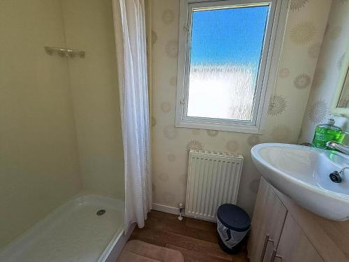 baño con lavabo, bañera y ventana en Lovely 8 Berth Caravan With Decking At California Cliffs In Norfolk Ref 50015J, en Great Yarmouth