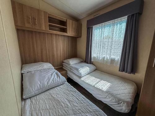 a small room with two beds and a window at Beautiful 8 Berth Caravan At Cherry Tree Holiday Park In Norfolk Ref 70803C in Great Yarmouth