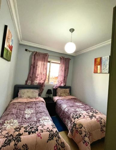 two beds in a small room with pink curtains at Résidence touristique Issounane in Afourer