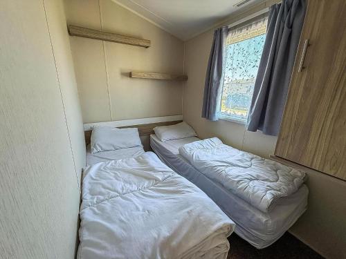 two beds in a small room with a window at 8 Berth Caravan With Decking At Caister Beach In Norfolk Ref 30016S in Great Yarmouth