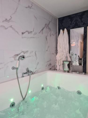 La salle de bains est pourvue d'une baignoire remplie d'eau verte. dans l'établissement Chambre d'Amour Jacuzzi Bordeaux Parking, à Bruges
