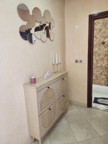 a room with a wooden dresser with clocks and candles at Dar mayssane in Agadir