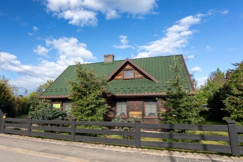 a house with a green roof and a fence at Dom pod Lipą in Jaminy