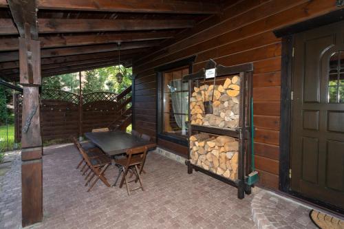a wooden cabin with a table and a stack of fire wood at Dom pod Lipą in Jaminy