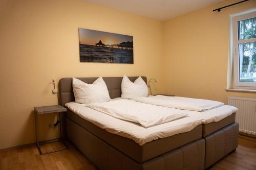 een bed met witte lakens en kussens in een kamer bij Ostseepark Waterfront-Karavelle in Heringsdorf