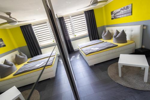 two beds in a room with yellow walls at Pension Village in Naumburg