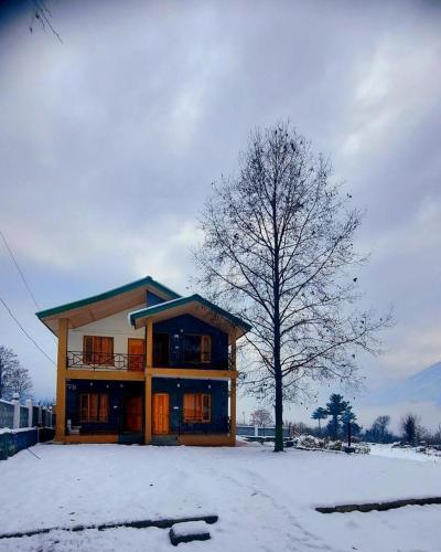 ein Haus mit einem Baum im Schnee in der Unterkunft Reconnect By GoingZero in Manali