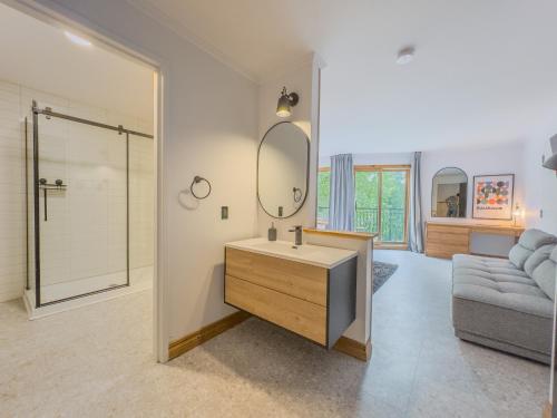 un bagno con lavandino, specchio e divano di Domaine du lac long- Piscine & Spa- a Saint-Alphonse-Rodriguez