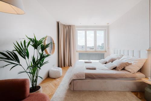 a white bedroom with a large bed and a plant at BeComfy - Old town apartment Bratislava in Staré Mesto