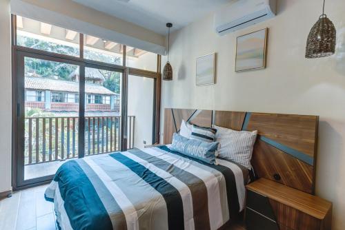 a bedroom with a bed and a large window at Amazing 2 bedrooms apartment with a pool in Sayulita in Sayulita