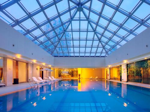 a large swimming pool with a glass ceiling at Hongrui Jinling Grand Hotel Hefei in Hefei