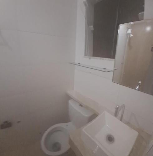 a bathroom with a white toilet and a sink at Apartamento Garden in Muriaé