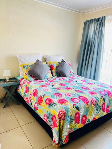 a bed with a colorful comforter and pillows at The Barberton Nest in Barberton