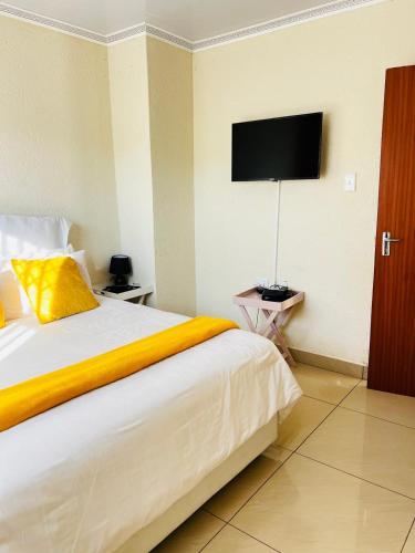 a bedroom with a large bed with a television on the wall at The Barberton Nest in Barberton