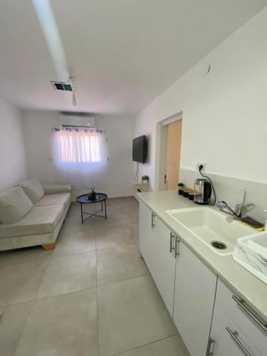 Una cocina blanca y una sala de estar con un sofá. en אירוח בעיר, en Kiryat Shemona