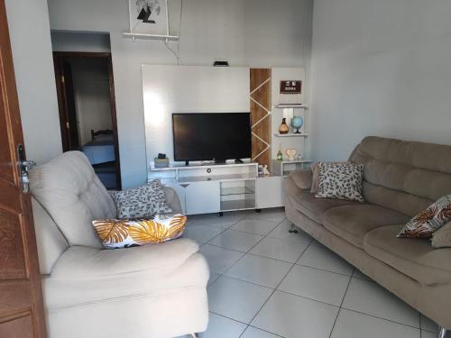 a living room with two couches and a flat screen tv at Temporada em Piúma in Piúma