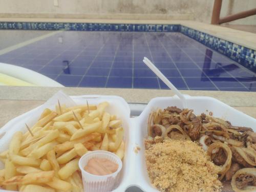 a tray of food with french fries and onion rings at Pousada Ondas do Mar Cabo Frio in Cabo Frio