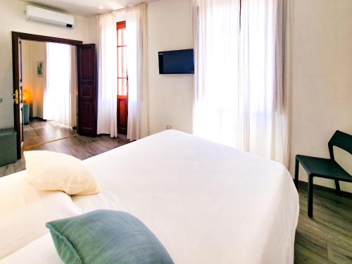 a bedroom with a white bed and a chair at Il Caracolo Rooms in La Maddalena