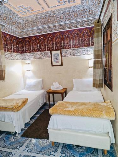 two beds in a room with a ceiling at Riad Dar Essassi 23 in Marrakech
