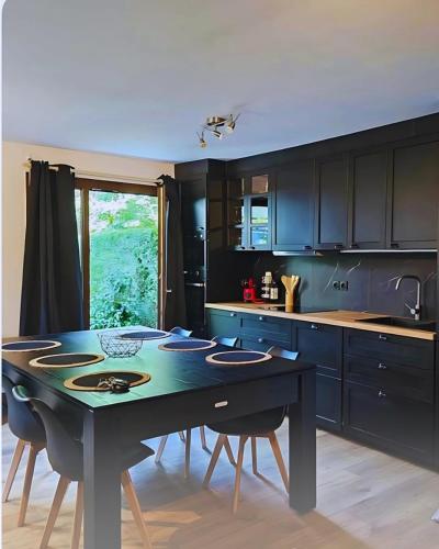 une cuisine avec une table et des chaises et une cuisine avec des armoires noires dans l'établissement Greenloft La tonnelle, à Annecy