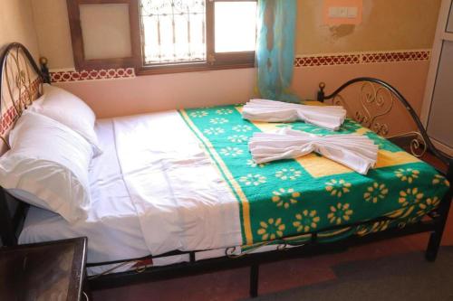 a bed with a green and white blanket on it at Gite d'étape Tafsoute in Tameskikt