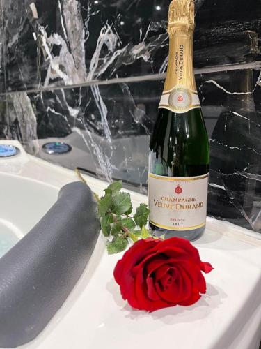 - une bouteille de champagne et une rose rouge dans la baignoire dans l'établissement Atypical romantic room, à Jassans-Riottier