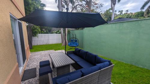 a patio with a blue couch and an umbrella at MoBay Las Palmas in Montego Bay