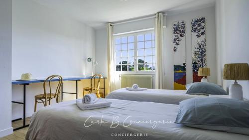 une chambre avec deux lits et un bureau et une fenêtre dans l'établissement La Maison des Plages Concarneau, à Concarneau