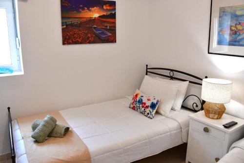 a white bed in a room with a lamp at Da Vinci kavouropetra in Aegina Town