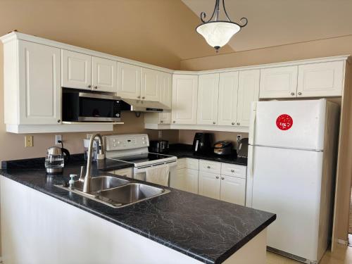 a kitchen with white cabinets and a white refrigerator at Saskatoon Lashyn Cove Homestay in Saskatoon