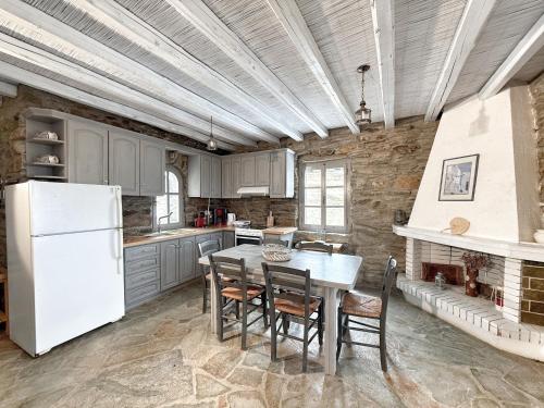 a kitchen with a table and a white refrigerator at The Traditional Stone Villa in Koundouros