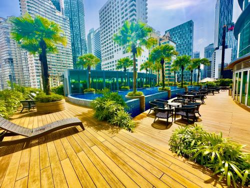 a deck with tables and chairs and palm trees in a city at Vortex Suites in Kuala Lumpur