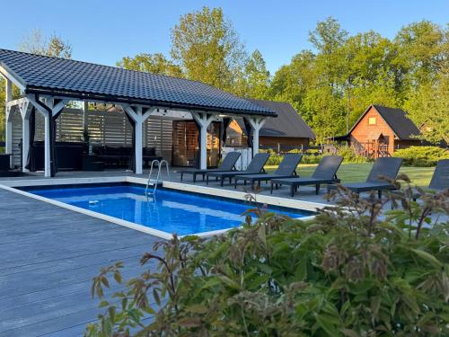 a swimming pool with a pavilion and chairs around it at Domek pod Karpaczem in Miłków