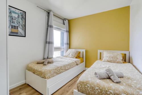 deux lits dans une chambre aux murs jaunes dans l'établissement Large - Paris, DisneyLand, Villepinte Expo, CDG, à Sevran