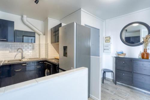 une cuisine avec un réfrigérateur en acier inoxydable et des armoires bleues dans l'établissement Large-Paris, CDG, Villepinte Expo, Disney, Asterix, à Sevran