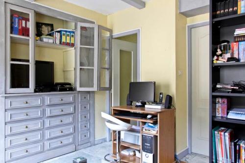 Cette chambre comprend un bureau avec un ordinateur et une télévision. dans l'établissement Studio climatisé au calme, terrasse vue colline, à Nice