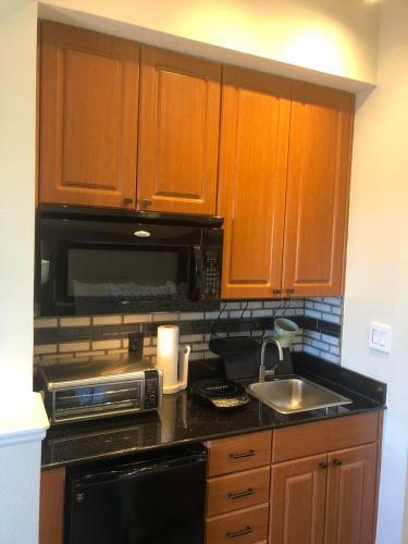 a kitchen with wooden cabinets and a sink and a microwave at Universal-Disney Dream 606H Studio - The Point in Orlando