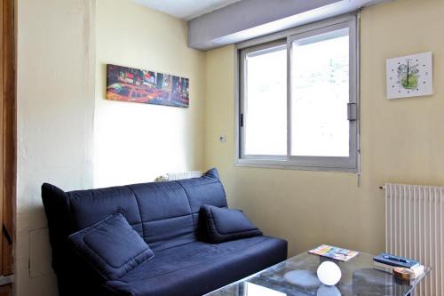un salon avec un canapé bleu et une fenêtre dans l'établissement Studio climatisé au calme, terrasse vue colline, à Nice