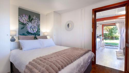 a bedroom with a bed and a door to a yard at Sea Breeze Apartment in Wilderness