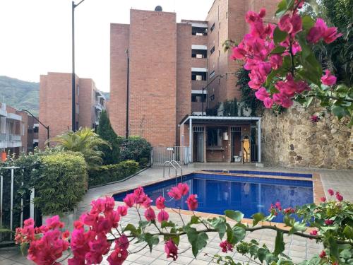 a pool in front of a building with pink flowers at Apartamento Entero Norte, a 25 min del Aeropuerto in Cali