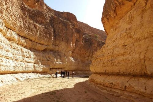 a group of people walking through a canyon at Dar Rouissi in Tozeur