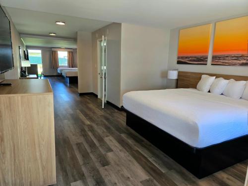 a hotel room with a bed and a flat screen tv at Days Inn and Suites by Wyndham Port Huron in Port Huron