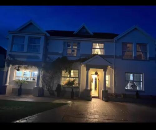 a white house with its lights on at night at Family & friends get together birthday hot tub in Porthcawl