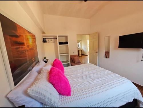 a bedroom with a white bed with pink pillows at Sunset in Sayulita