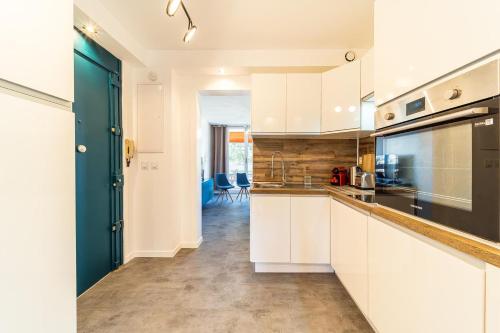 une cuisine avec des placards blancs et une porte bleue dans l'établissement T5 balcony Parking 10 min Eurexpo -Stade-ldlc, à Bron