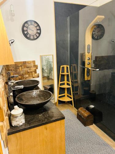 La salle de bains est pourvue d'un lavabo et d'une horloge murale. dans l'établissement La maisonnette, à Les Fumades-Les Bains