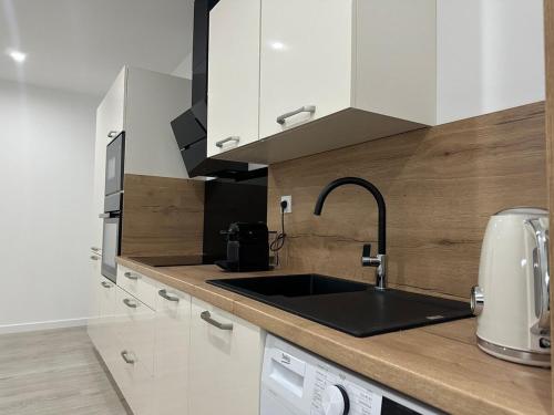 une cuisine avec des armoires blanches et un évier dans l'établissement Appartement cosy parking privé, à Tarbes