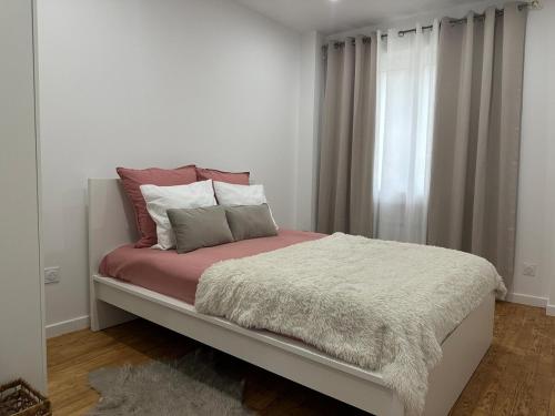 un lit dans une chambre blanche avec une fenêtre dans l'établissement Appartement cosy parking privé, à Tarbes