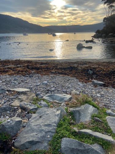 a group of rocks on the shore of a body of water at studio one bay view in Nubeena