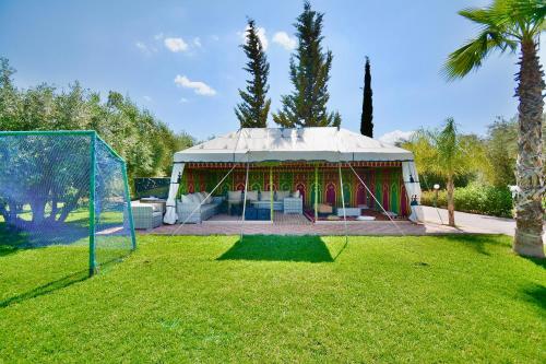 a gazebo in a yard with a palm tree at Ferme de vacances avec une grande villa à Marrakech in Marrakech
